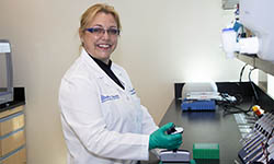 Dr. Sophie Paczesny stands at a counter in her lab and works with test tubes
